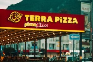 Vibrant neon sign of Terra Pizza restaurant illuminated in an urban setting at night.