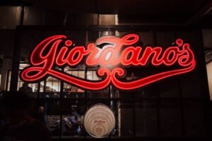 Illuminated Giordano's neon sign outside restaurant showcasing vibrant red glow at night.